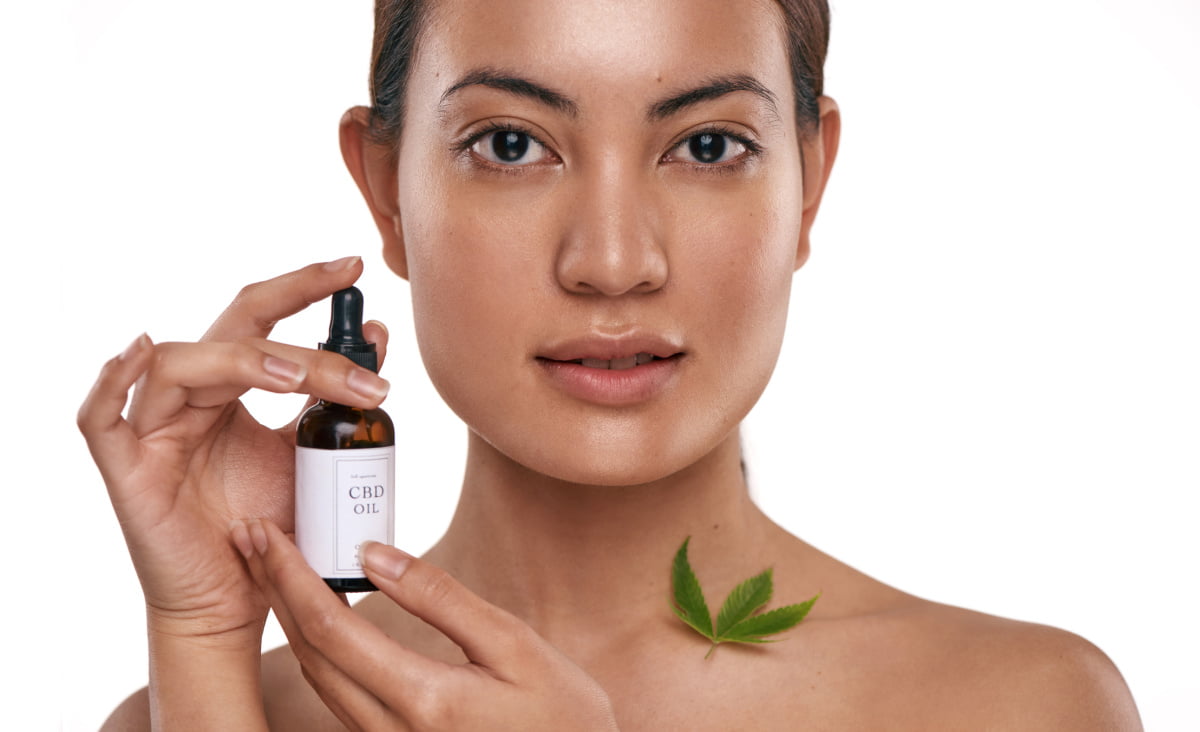 Beautiful Woman with Glowing Skin Holds bottle of CBD Oil for Skincare and Acne