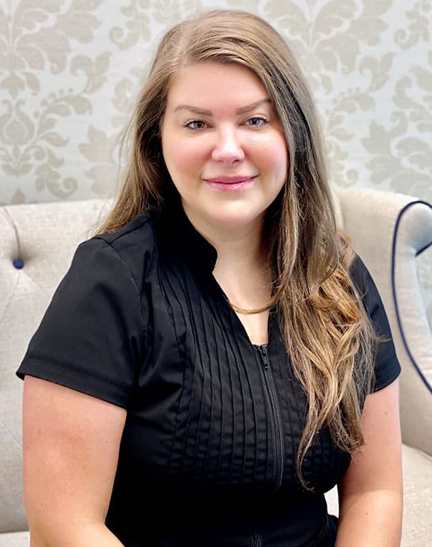 Aesthetician Holly seated in cream-colored armchair at Kalos Medical Spa