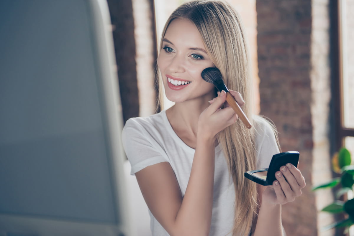 Young woman smiling and applying her daily makeup