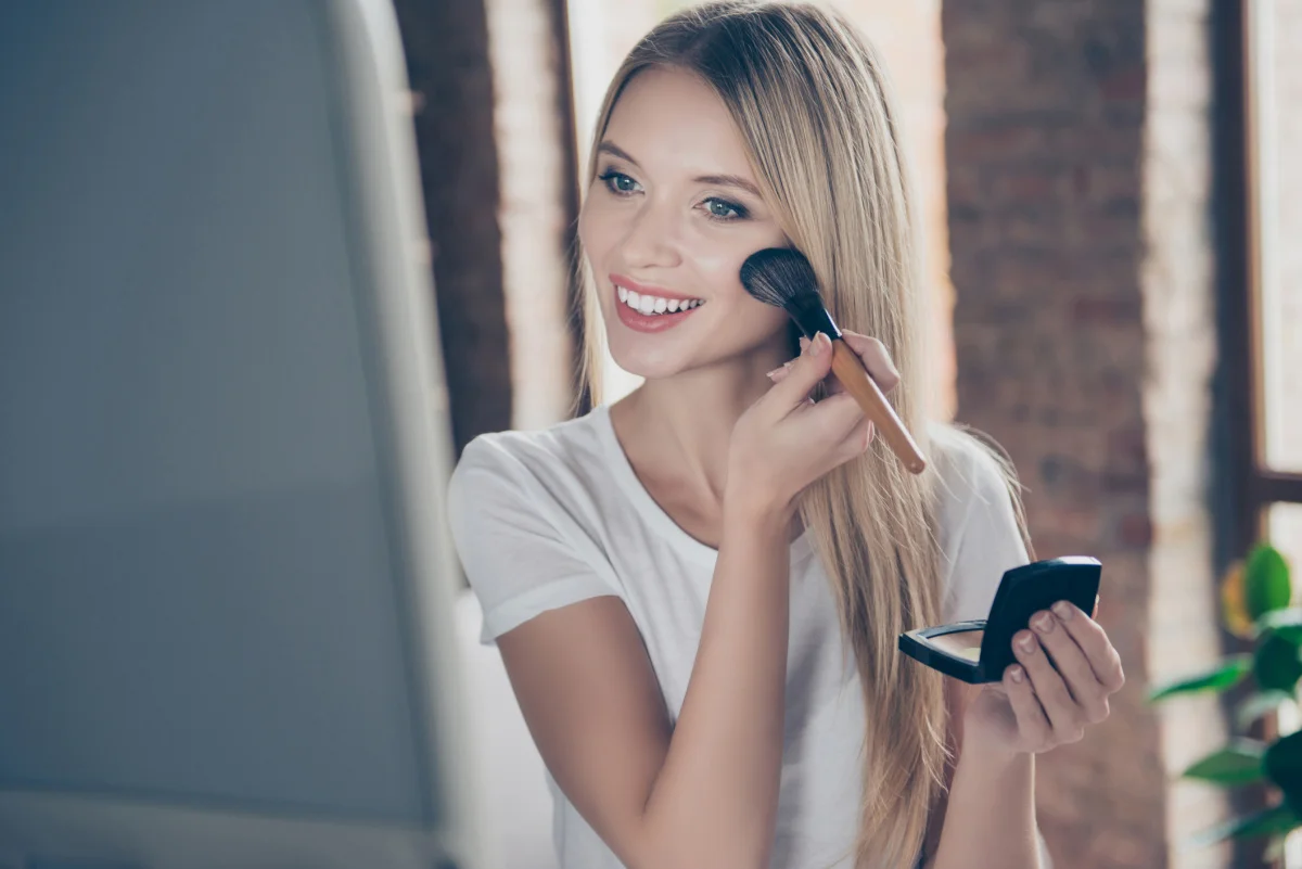 Young woman smiling and applying her daily makeup