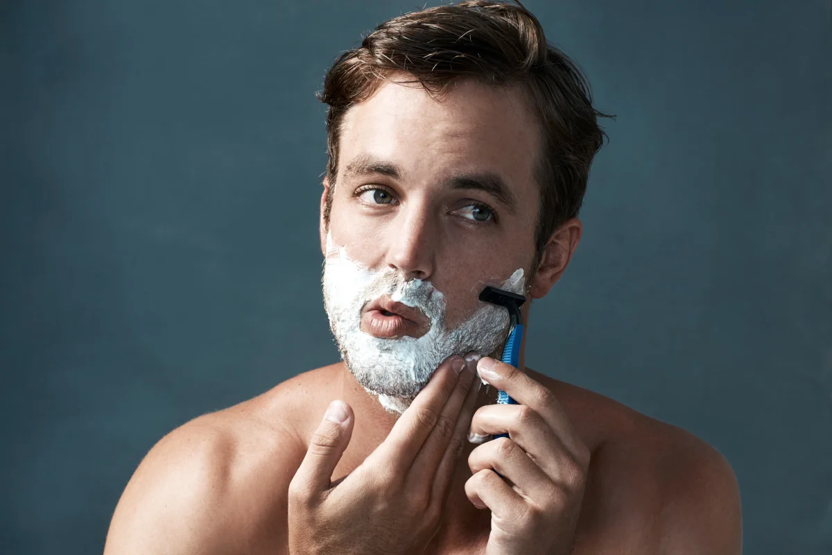 Young man shaving face and prepping skin before dermal filler treatment