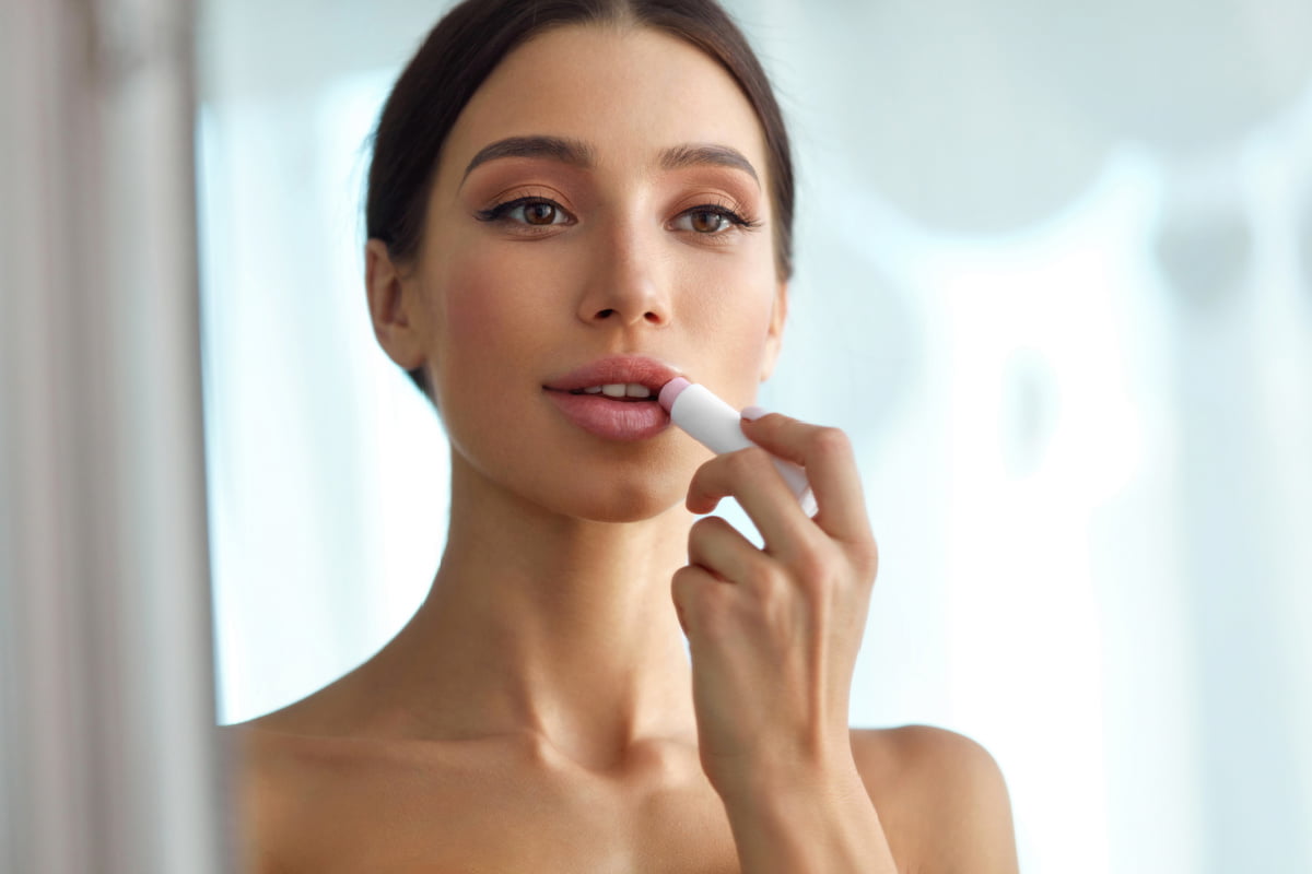 Woman applying moisturizing and hydrating lip product