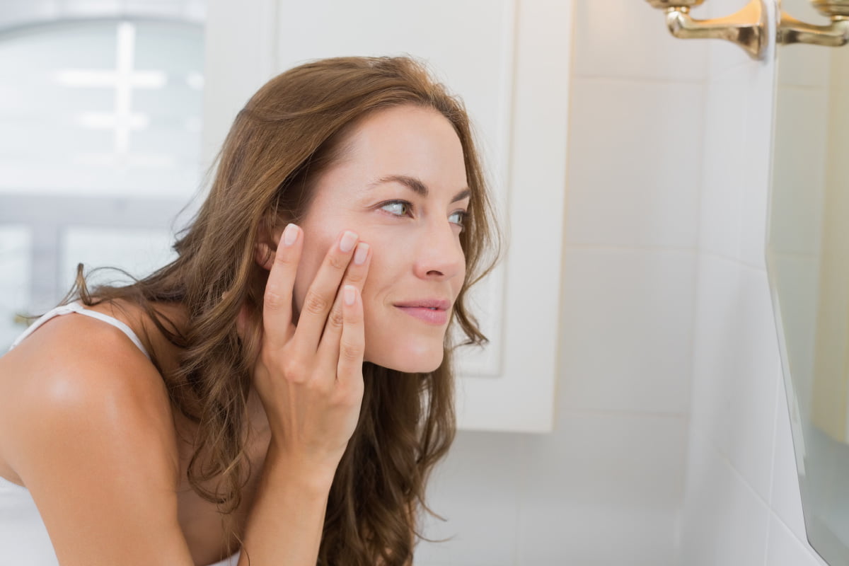 Woman touching skin looking in mirror