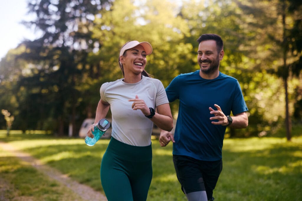Fit man and woman smiling on a run outside