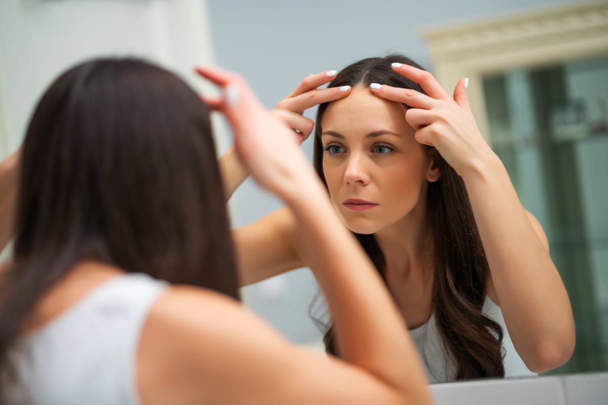 Woman looking at forehead muscles in the mirror after getting Botox injections