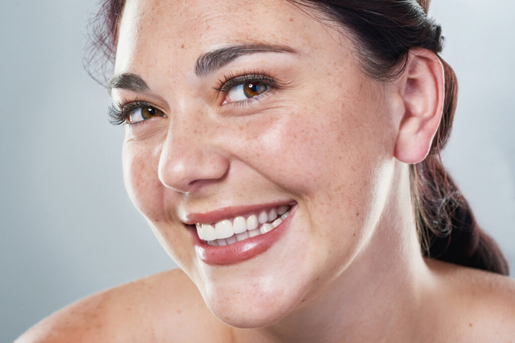 Close up of smiling young woman with freckled skin