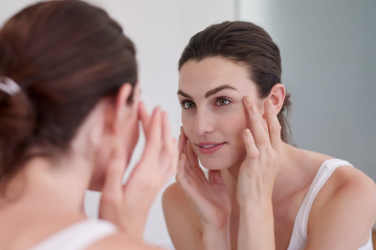 Woman looking at skin up close in mirror