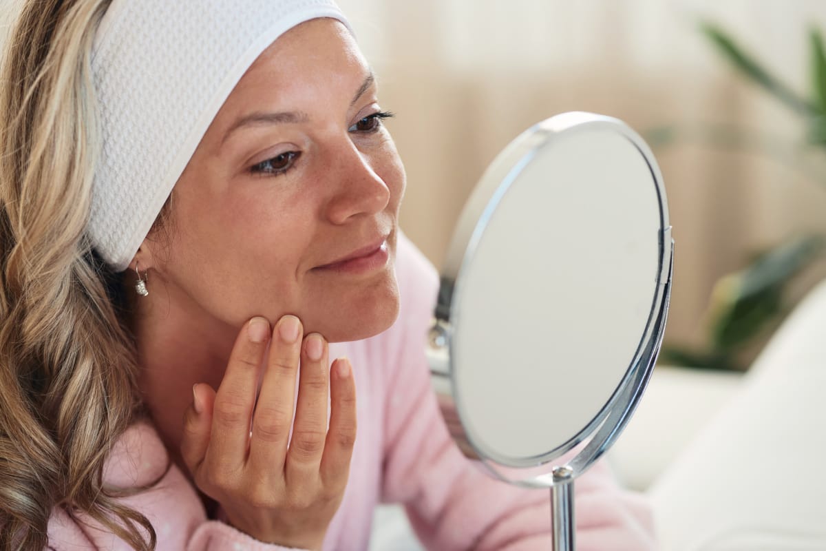 Woman touching face in mirror