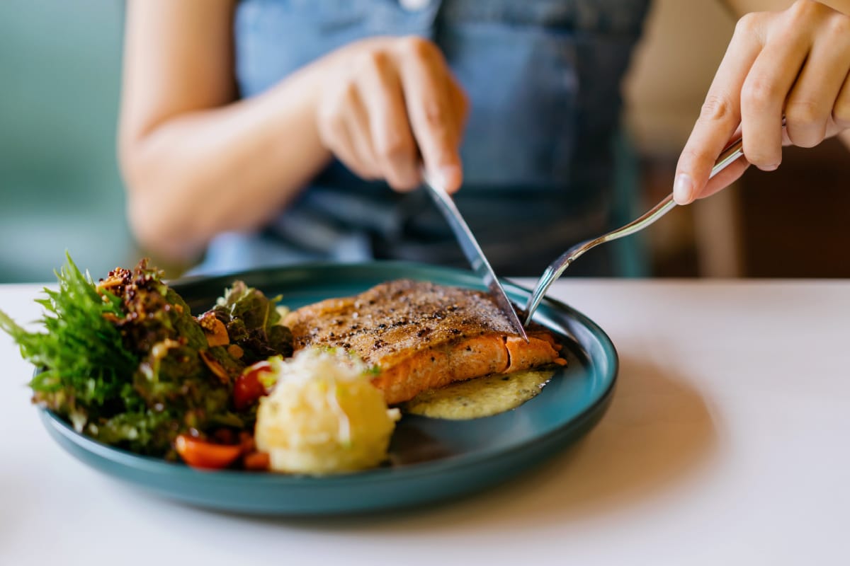 Woman eating grilled salmon and salad