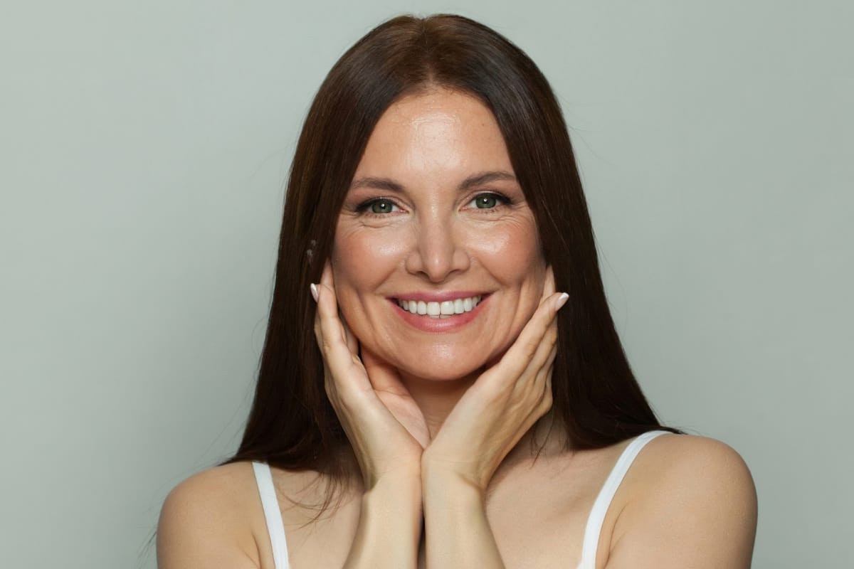 Mature woman smiling touching face and lifting cheeks